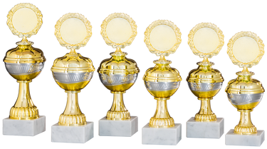 Sechs goldene und silberne Pokale Marburg 6-er Pokalserie 208 mm – 255 mm PK758580-6-E50 mit runden Plaketten und Sockeln aus weißem Marmor sind in einer Reihe angeordnet und zeigen ein exklusives Design.